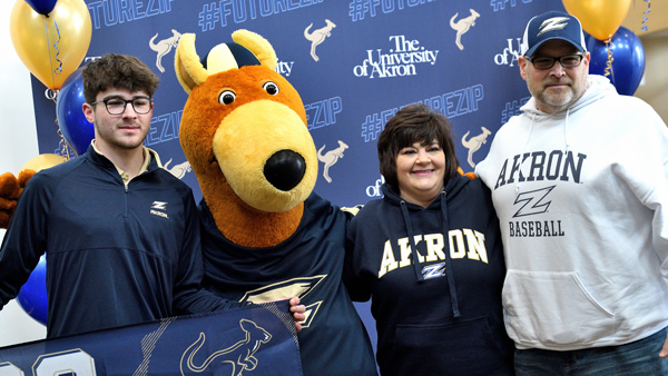 Sibling and parents of college student stand with her holding large blue letters that spell UA