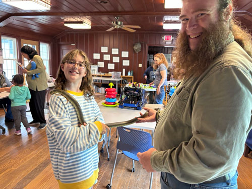 young child holding snake with adult male