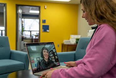 University of Akron student participates in a video call on a laptop while studying in a campus lounge.