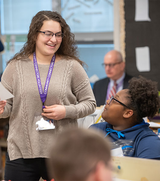 University of Akron education student works with a K-12 student in a classroom, providing guidance during a lesson.