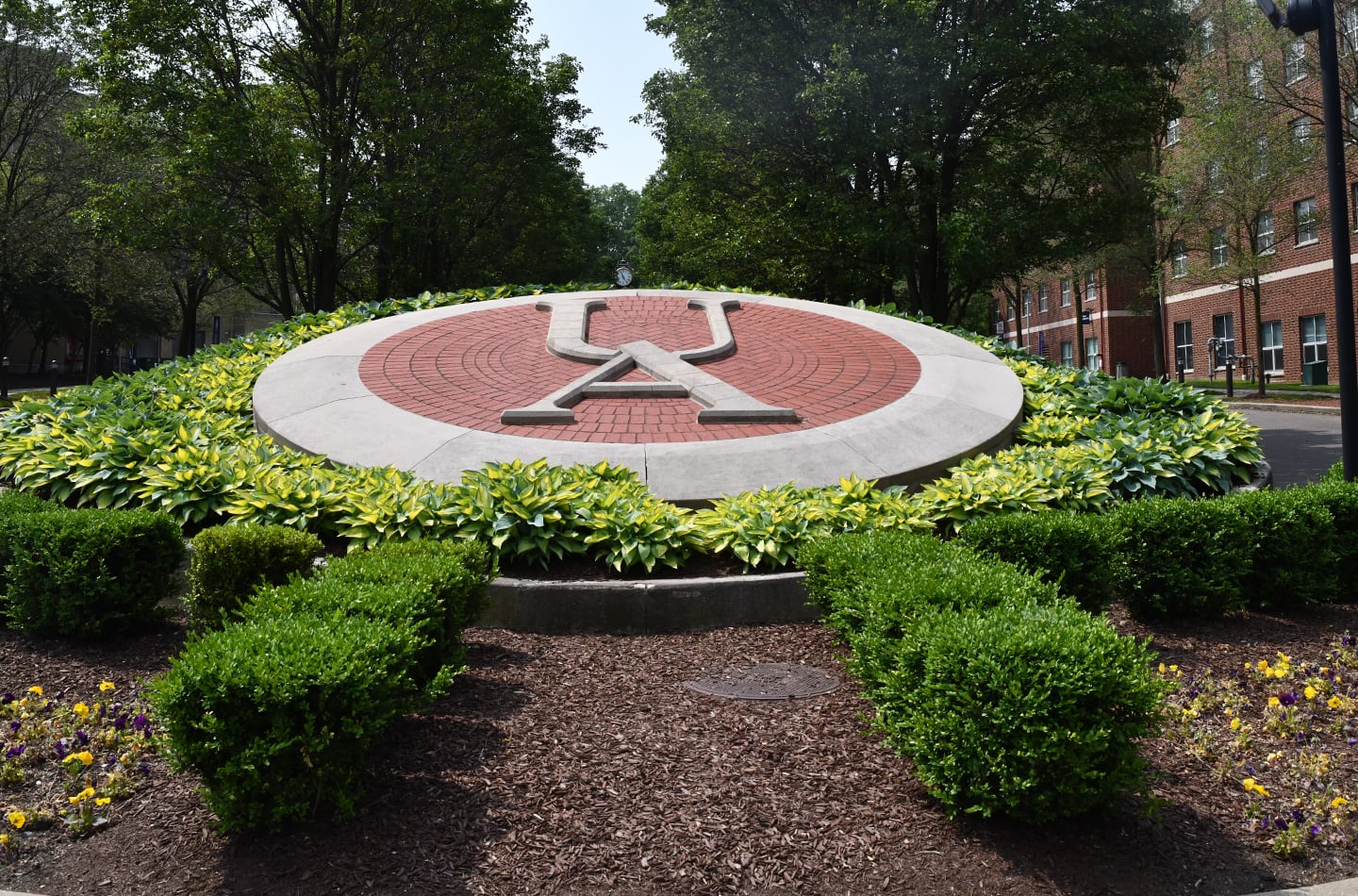 A large, circular stone and brick campus seal featuring the 
