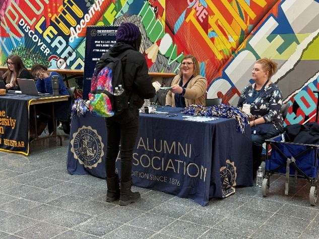 Student speaking to Alumni Office team members who are tabling