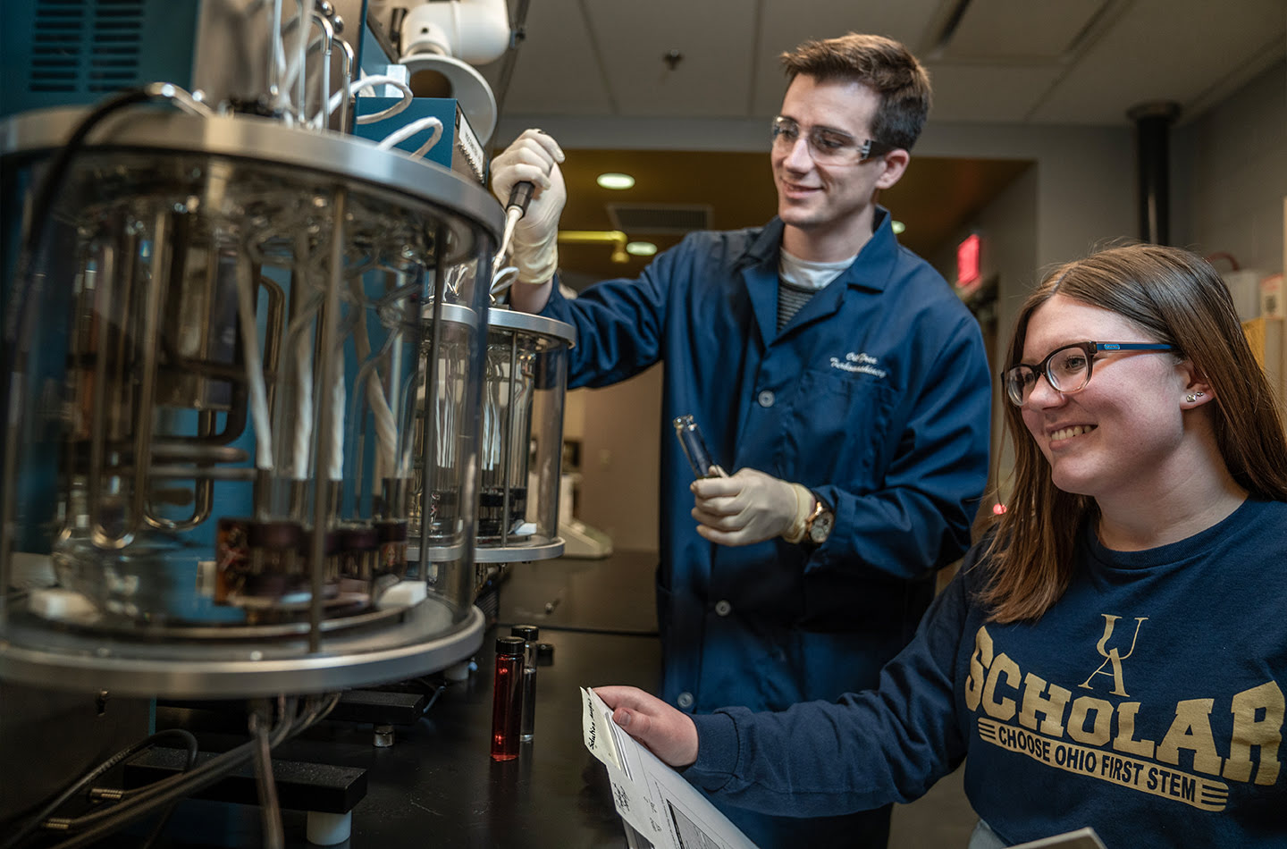 An engineering student and a professor standing in front of engineering equipment