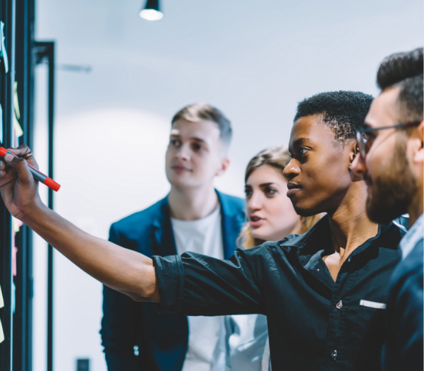 Young men and women drawing on a wall whiteboard