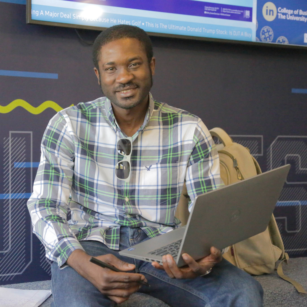 Student in plain shirt holding laptop