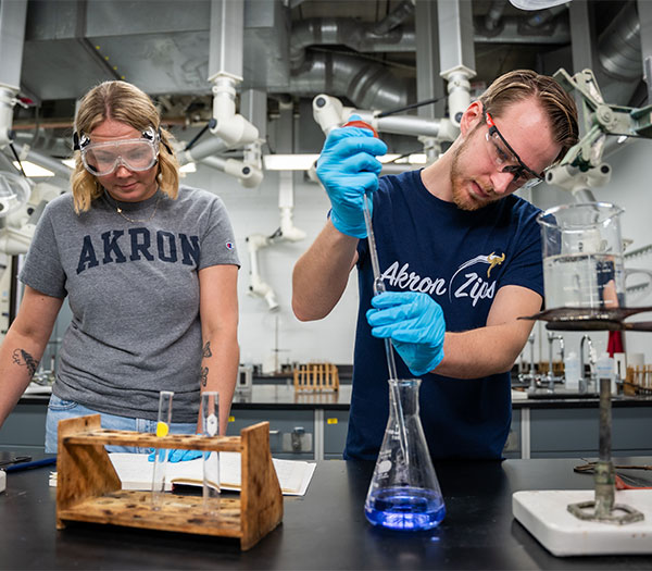 University of Akron chemistry students conduct an experiment in a laboratory while measuring and mixing liquids in glassware.
