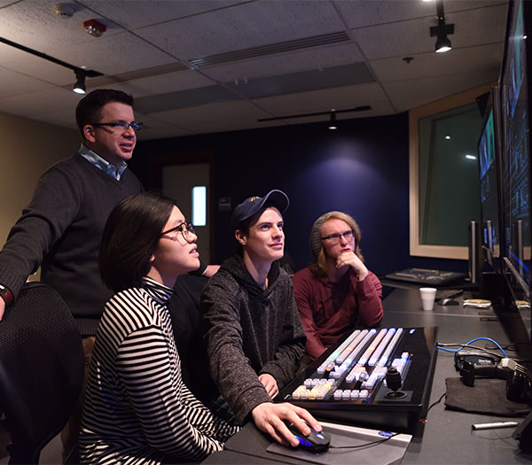 students work with a faculty member in ZTV television production control room, monitoring and editing live video content.