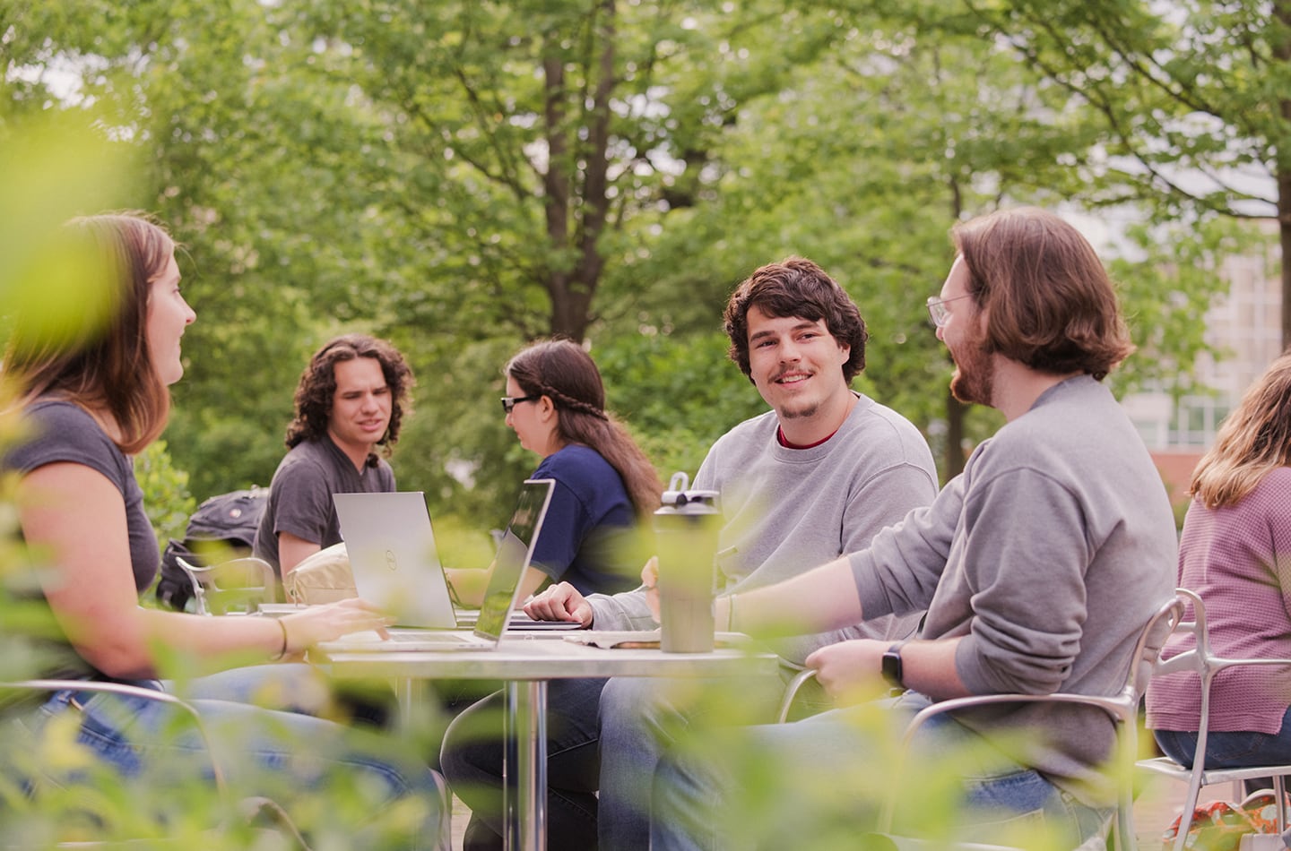 Students gathered at a table outside, conversing