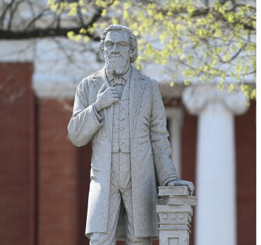 Buchtel statue in the foreground with Buchtel Hall blurred in the background.