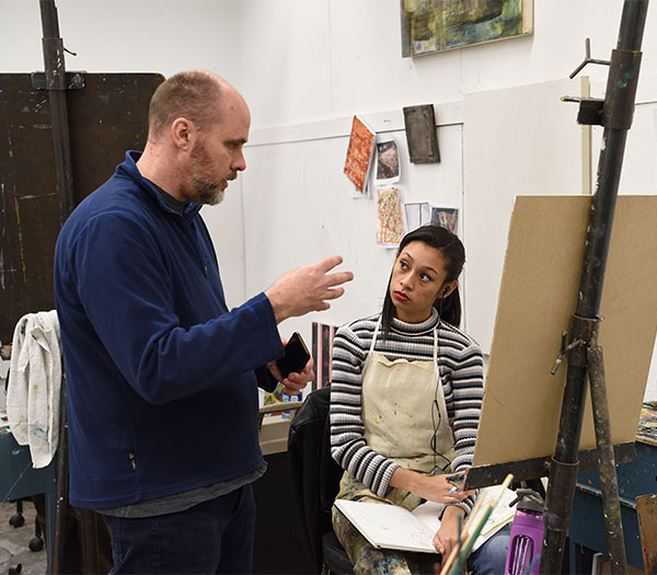 Painting instructor discusses a student’s work with her in the studio.