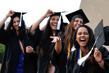 Group of graduates in caps and gowns celebrating and cheering at commencement.