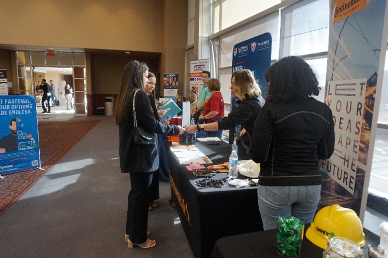 Photo of a student talking with an employer at their table at a career fair in the UA Student Union ballroom.