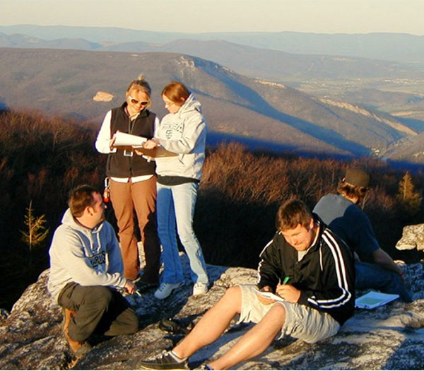 University of Akron geology students record observations and take notes while conducting fieldwork on a rocky mountain overlook.