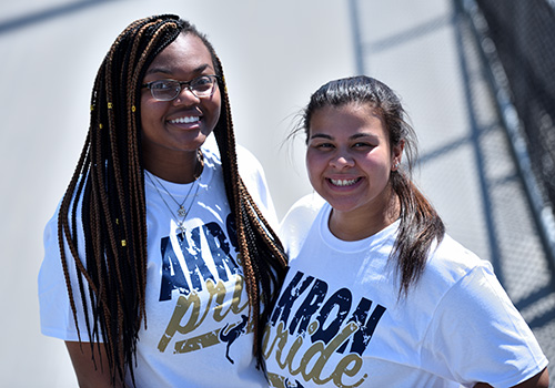 Two students smile at the camera.