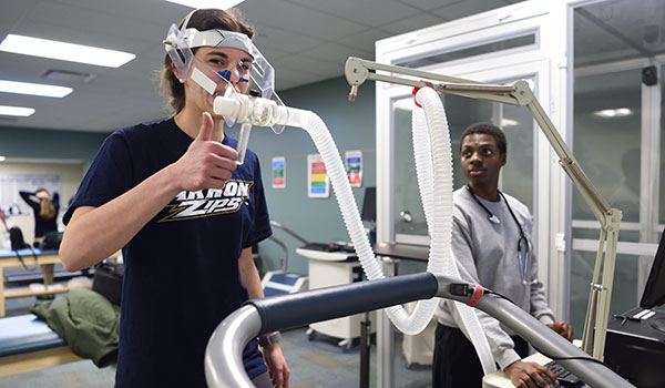 Student monitoring health stats while another student exercises.