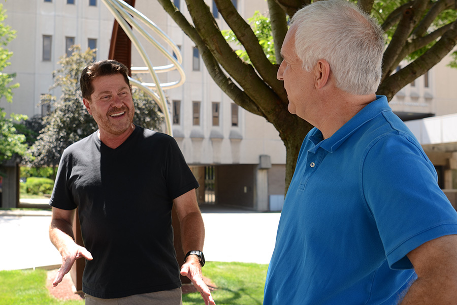 Two men on UA campus on a sunny day.