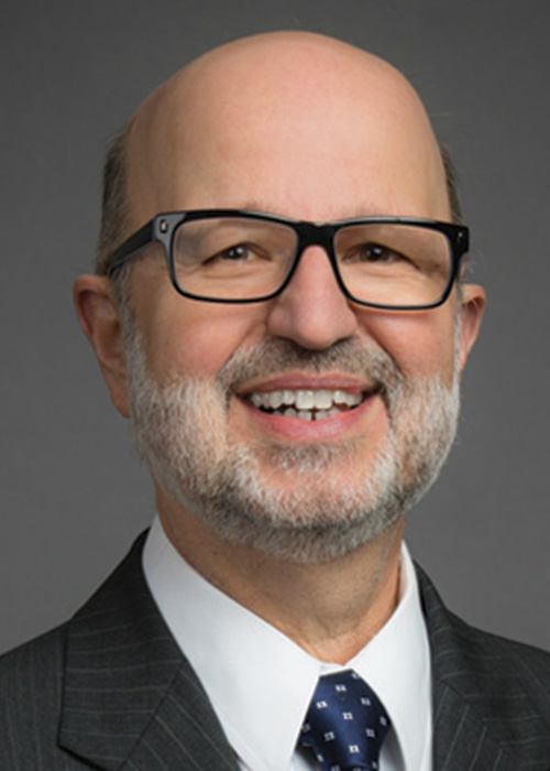 Photo of man in suit against gray background.