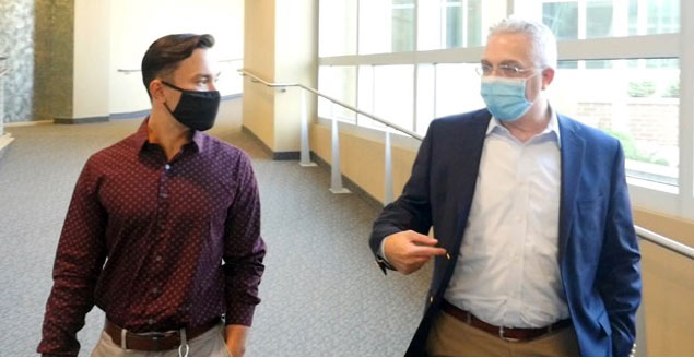 Two men walking in a hallway, having a confersation